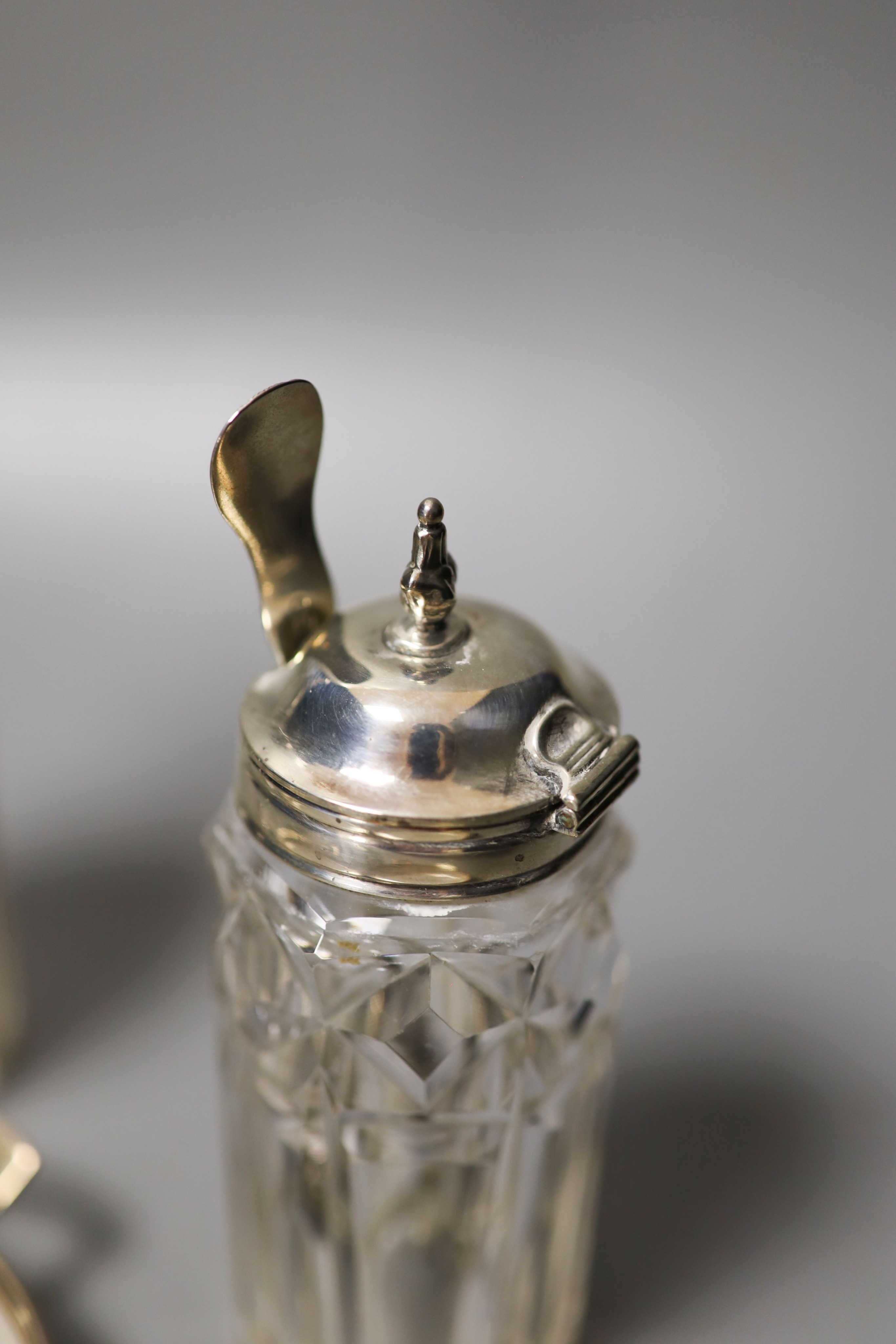 A pair of modern silver mounted glass butter dishes, a silver toastrack, three silver mounted glass bottles and three pairs of silver sugar tongs.